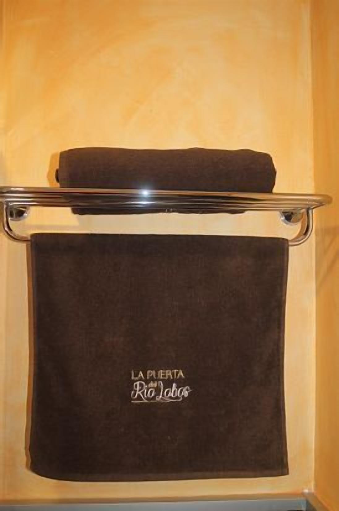 Una toalla colgada en un perchero metálico con el texto "LA PUERTA Rio Labos".