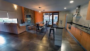 A modern kitchen with a dining area, stone accents, and a large window. - Self catering La Puerta del Rio Lobos for 10 people (San Leonardo de Yague)