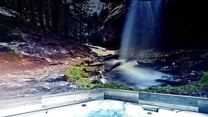 A hot tub in a forested area with a waterfall in the background. - Self catering La Puerta del Rio Lobos for 10 people (San Leonardo de Yague)
