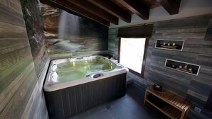 A spa room with a hot tub, wooden bench, and a waterfall mural. - Self catering La Puerta del Rio Lobos for 10 people (San Leonardo de Yague)