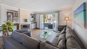Een moderne woonkamer met een bank, een glazen salontafel en een boekenkast.