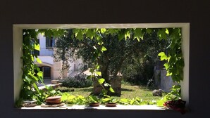 A window with a view of a garden, including potted plants and a stone structure. - Villa with private pool - sea view near WWF natural oasis (Carovigno)