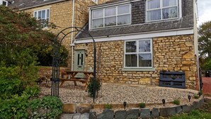 A stone house with a wooden door, a small garden with pebbles, and a wooden bench. - Durham, 3 bedroom Cottage in village location near Durham city,  pet friendly (Sherburn Village)