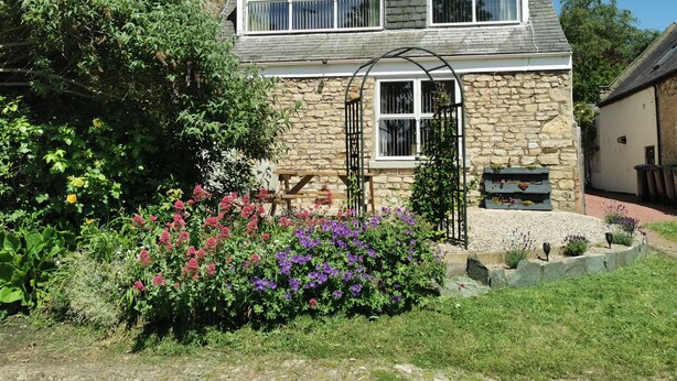 A stone house with a garden in front, a wooden bench, and a metal gate. - Durham, 3 bedroom Cottage in village location near Durham city,  pet friendly (Sherburn Village)
