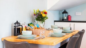 A dining table set with plates, bowls, and a coffee pot, with a vase of flowers and a basket of snacks on the table. - Durham, 3 bedroom Cottage in village location near Durham city,  pet friendly (Sherburn Village)