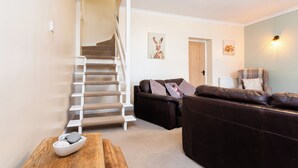 A living room with a staircase, a brown leather sofa, and a wooden coffee table. - Durham, 3 bedroom Cottage in village location near Durham city,  pet friendly (Sherburn Village)