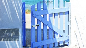 Un bâtiment blanc avec une porte bleue qui mène à une plage.