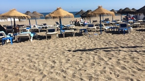 A beach with rows of sun loungers and thatched umbrellas. - EASY WALK TO MAX BEACH LOVELY APT  WI-FI  STUNNING SEA/POOL VIEWS +ELEVATOR/LIFT (Riviera del so/l La cala)