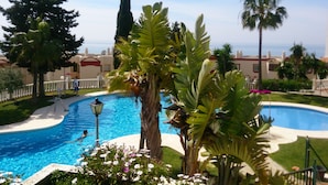 A swimming pool surrounded by tropical plants and a view of the sea. - EASY WALK TO MAX BEACH LOVELY APT  WI-FI  STUNNING SEA/POOL VIEWS +ELEVATOR/LIFT (Riviera del so/l La cala)
