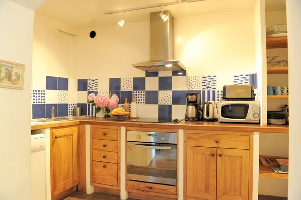 Una cocina con gabinetes de madera, una campana extractora de acero inoxidable, un microondas y una cafetera.