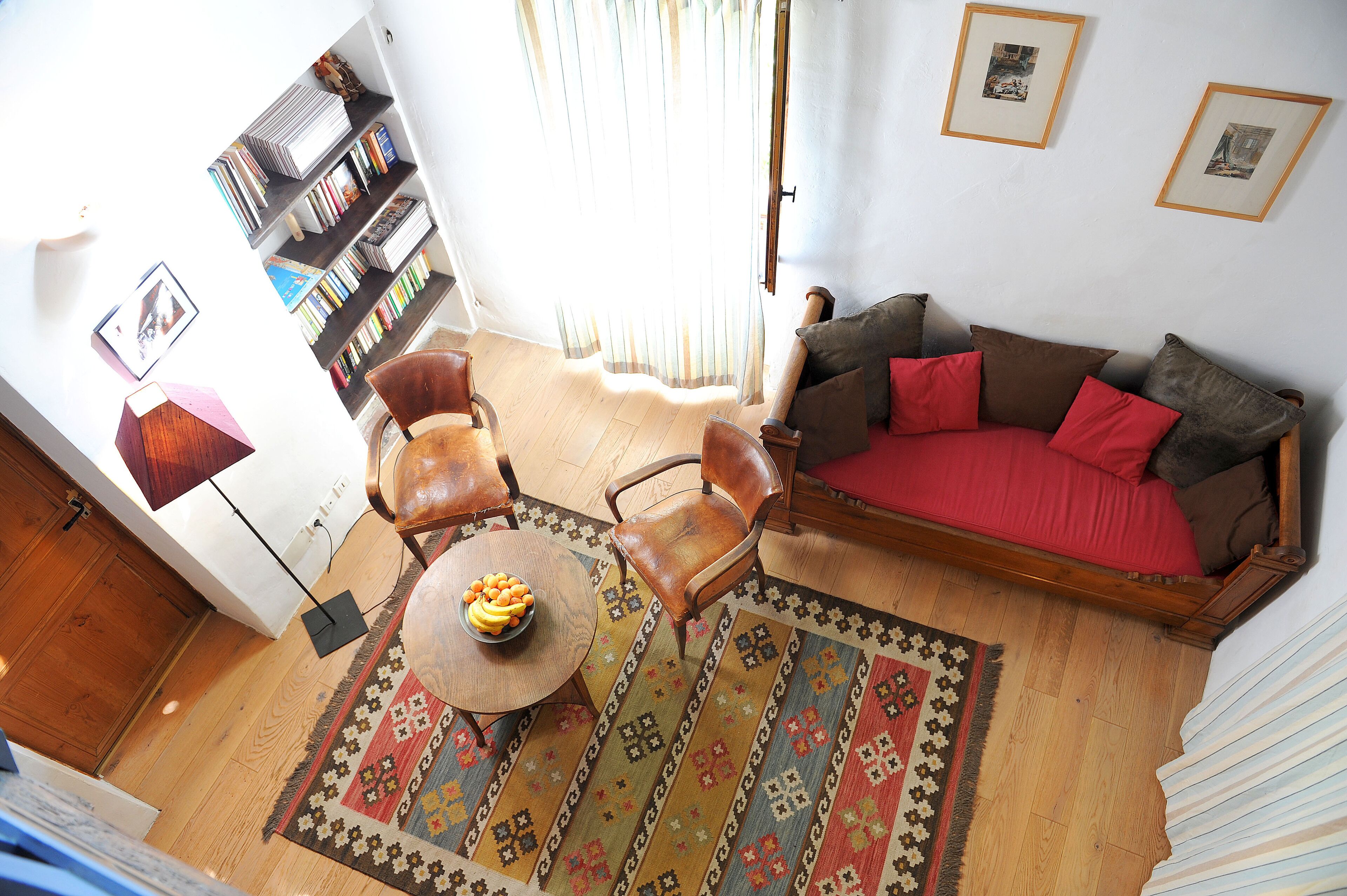 Un salon comprenant un canapé, des fauteuils, une table basse, une bibliothèque et un tapis à motifs.