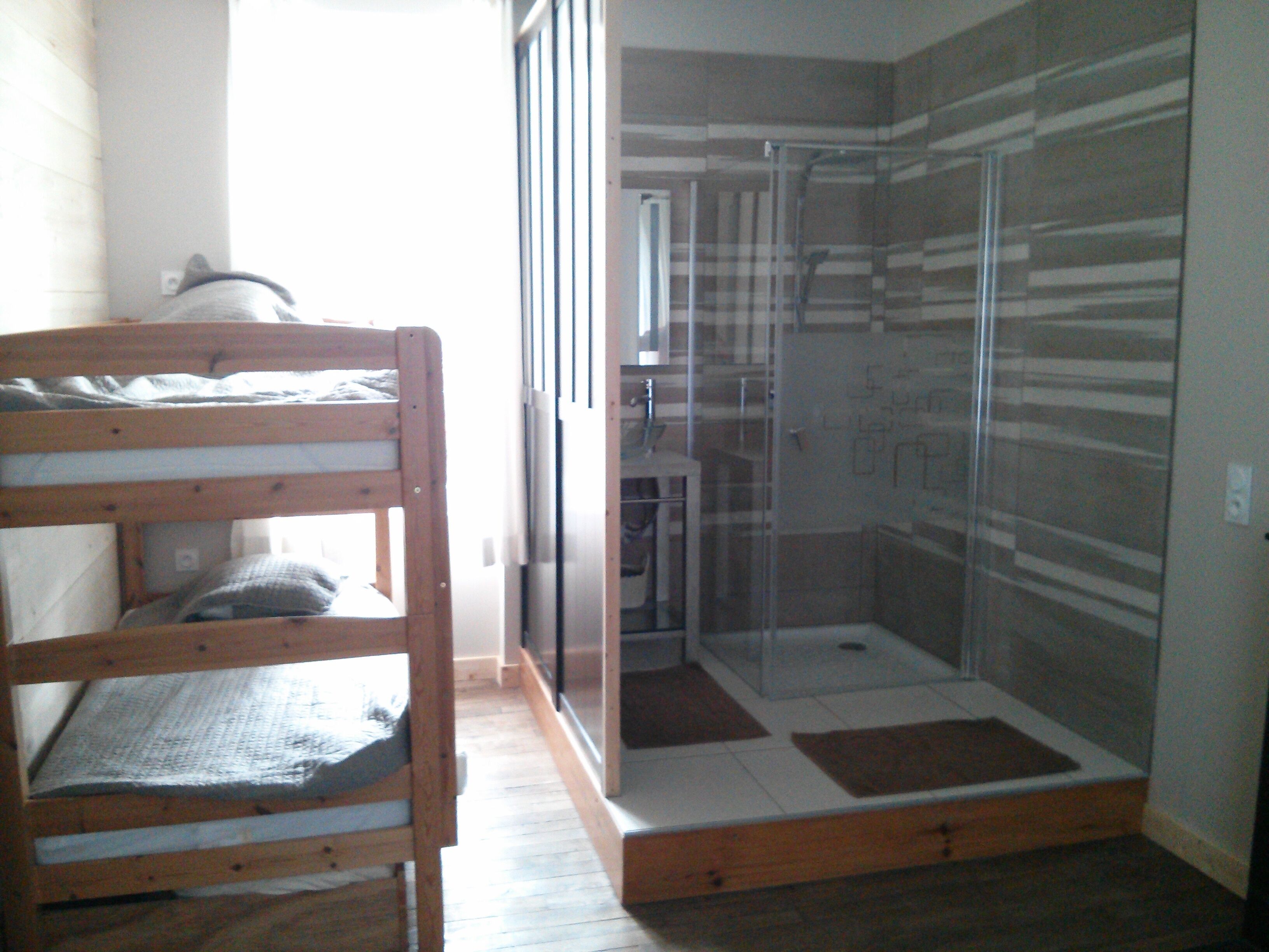 Ein Zimmer mit einem Etagenbett, einer Dusche mit Glastür und einem Fliesenboden.