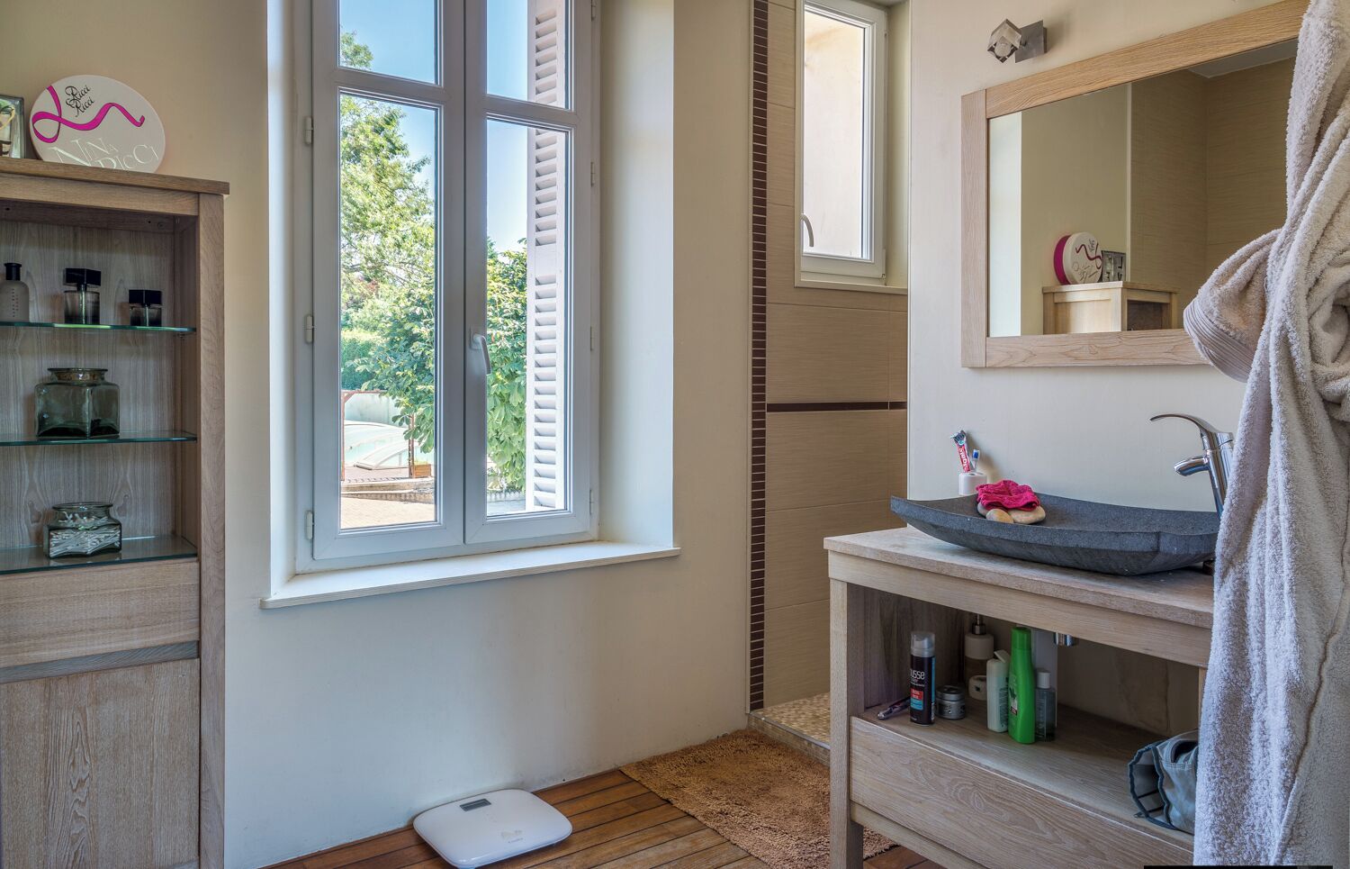 Une salle de bain avec une grande fenêtre, une balance, un lavabo et un miroir.
