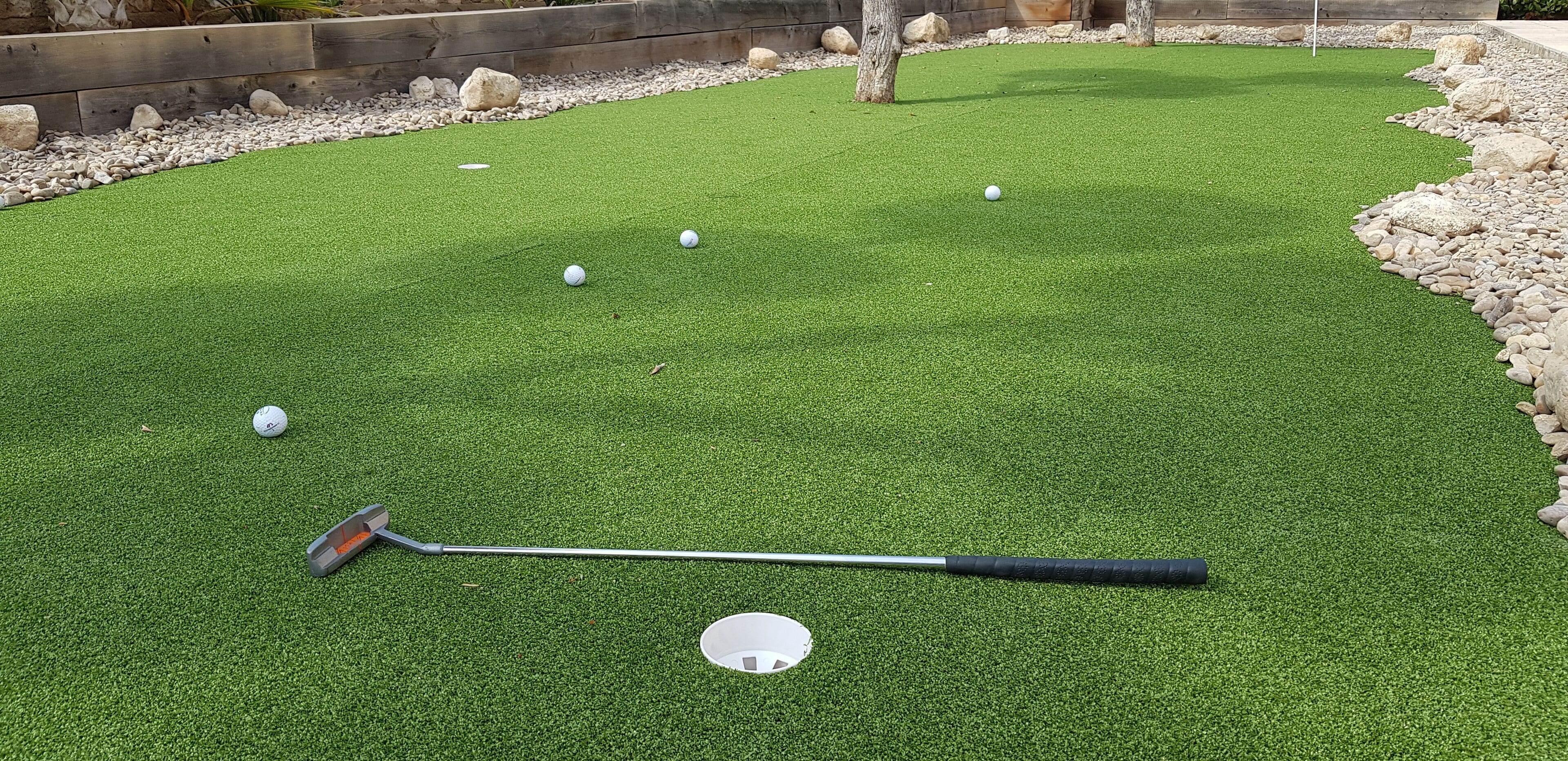 A miniature golf course with a putting green, a golf hole, and a golf club.