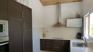 A modern kitchen with dark cabinets, a stainless steel range hood, and a window providing natural light.