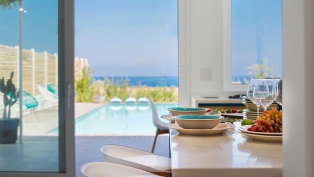 Un espace repas avec vue sur une piscine et la mer.