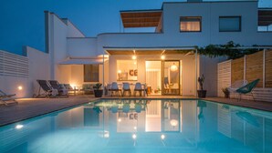 Une maison moderne dotée d’une piscine, d’un espace extérieur aménagé et d’une entrée bien éclairée.