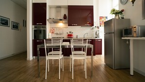 Une cuisine moderne dotée d’un îlot central, d’appareils électroménagers en acier inoxydable et d’un coin repas avec des chaises blanches.