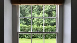 Ein Fenster mit Blick auf einen Garten und eine Steinmauer.