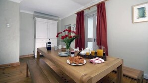 Ein Holztisch mit Frühstücksangeboten, einer Blumenvase und einem roten Vorhang.
