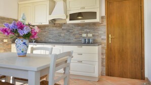 Une cuisine avec des meubles blancs, un pare-feu en pierre, un four à micro-ondes et une porte en bois.