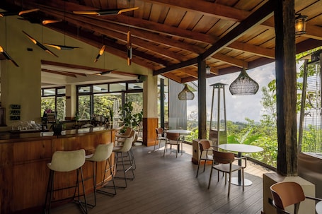 A spacious outdoor bar area with wooden flooring, bar stools, and hanging pendant lights.