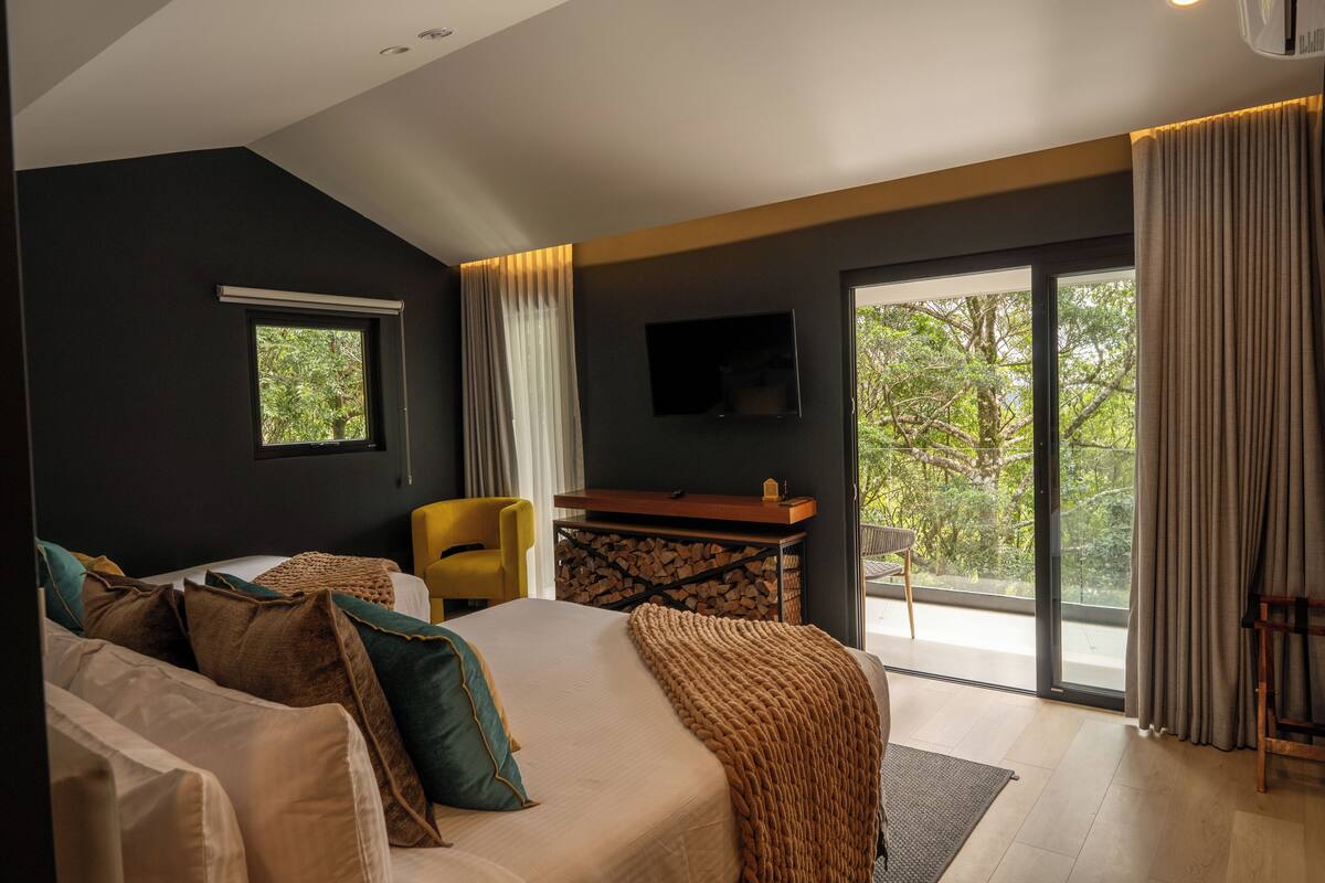 A modern hotel room with a large bed, a desk, a chair, and a TV.