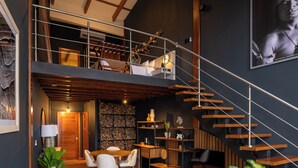 A modern loft with a wooden staircase, a dining area, and a living space with a large plant. - Koora Hotel by Sandglass (Monteverde)