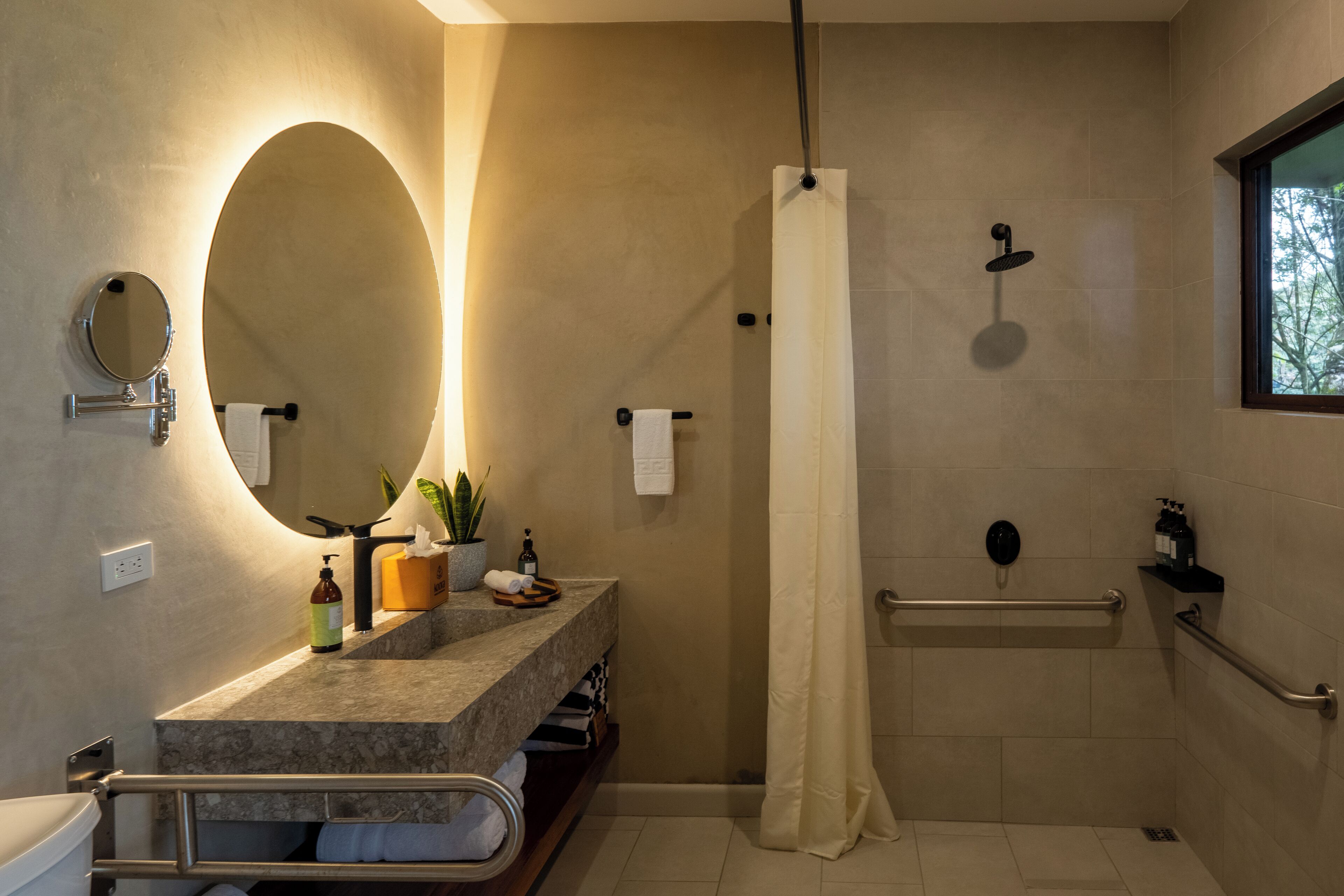 A modern bathroom with a shower, a sink with a mirror, and a window.