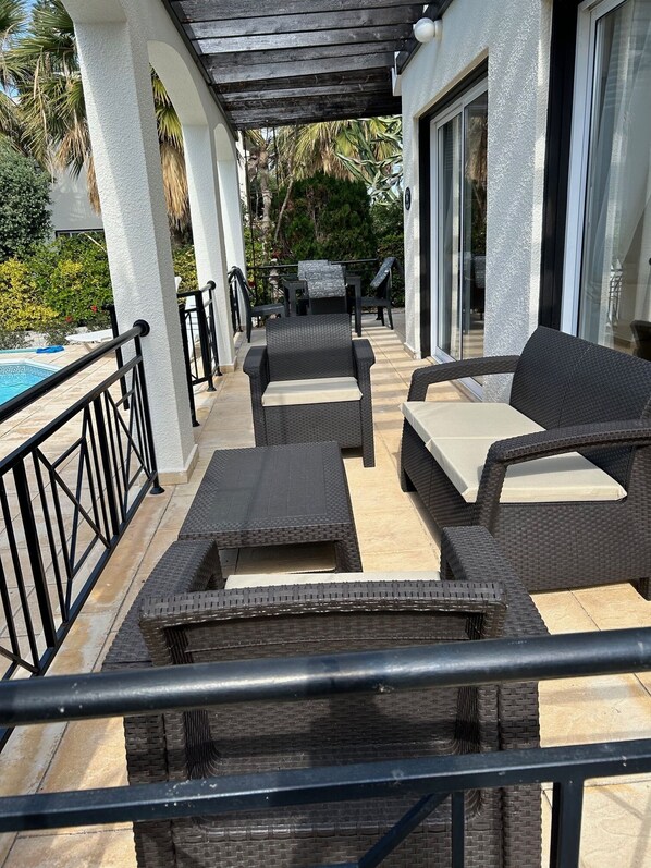 An outdoor patio with wicker furniture, a pool, and a covered area with a pergola.