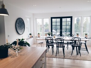 Enjoy meals with family and friends in this spacious dining area, surrounded by large windows and lush greenery.