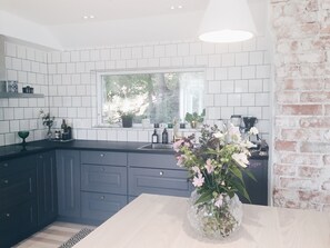 Enjoy a modern kitchen with a large window offering a view of lush greenery, a dark countertop, and a brick accent wall.