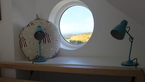 A desk with a lamp, a fan, and a window with a view of the landscape. - The Lookout - panoramic views; log fire; ONE-dog-friendly, local beaches. (Kingston)