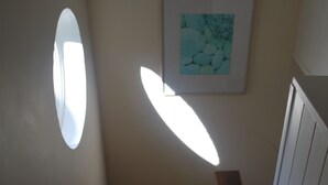 A staircase with a wooden handrail, a framed picture on the wall, and a window casting light on the stairs. - The Lookout - panoramic views; log fire; ONE-dog-friendly, local beaches. (Kingston)