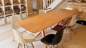 Zona pranzo con tavolo e sedie in legno, una scala e una libreria con diversi oggetti.