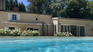 Una piscina con acqua cristallina e blu, circondata da una recinzione e fiori bianchi.