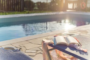 A poolside setting with a lounge chair, a book, and a pair of sunglasses. - Aeolus villa with private pool, stunning sea views,  beach in 5min, Wifi (Makrigialos)