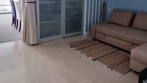 Moderni olohuone, jossa on beige sohva, lasiovi ja siniraidallinen seinä.