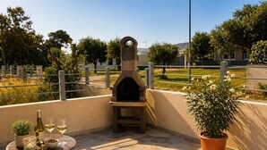 An outdoor patio with a stone-tiled floor, a small table with a potted plant, a wine bottle, and glasses. - Villa Etienne - Key to Villas (Valledoria)