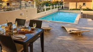 A rooftop pool area with a dining table set for two, surrounded by lounge chairs. - Villa Etienne - Key to Villas (Valledoria)