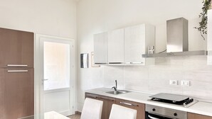 A modern kitchen with white cabinets, a stainless steel sink, and a built-in oven. - Villa Etienne - Key to Villas (Valledoria)
