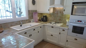 A kitchen with white cabinets, a sink, a stove, and a microwave.