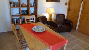 A dining area with a wooden table, chairs, a bookshelf, and a lamp.