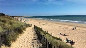 Una playa arenosa con una cerca de madera y un cielo despejado.