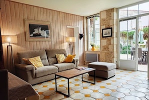 Una sala de estar con un panel de madera, un sofá, una mesa de centro y una pared de piedra con una ventana.