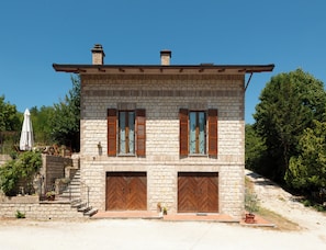 A two-story stone building with wooden shutters, a metal roof, and a paved entrance. - Small villa with a big garden and a big swimming pool - Sassoferrato (Sassoferrato)