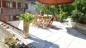 A patio with a table and chairs, a large umbrella, and a decorative owl statue.