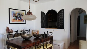 A dining area with a wooden table, chairs, a bowl, and a hanging light fixture. - Rustic apartment in Praia de Carvoeiro, Algarve (Carvoeiro)