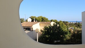 A view through a window of a building with a tiled roof, satellite dish, and trees. - Rustic apartment in Praia de Carvoeiro, Algarve (Carvoeiro)