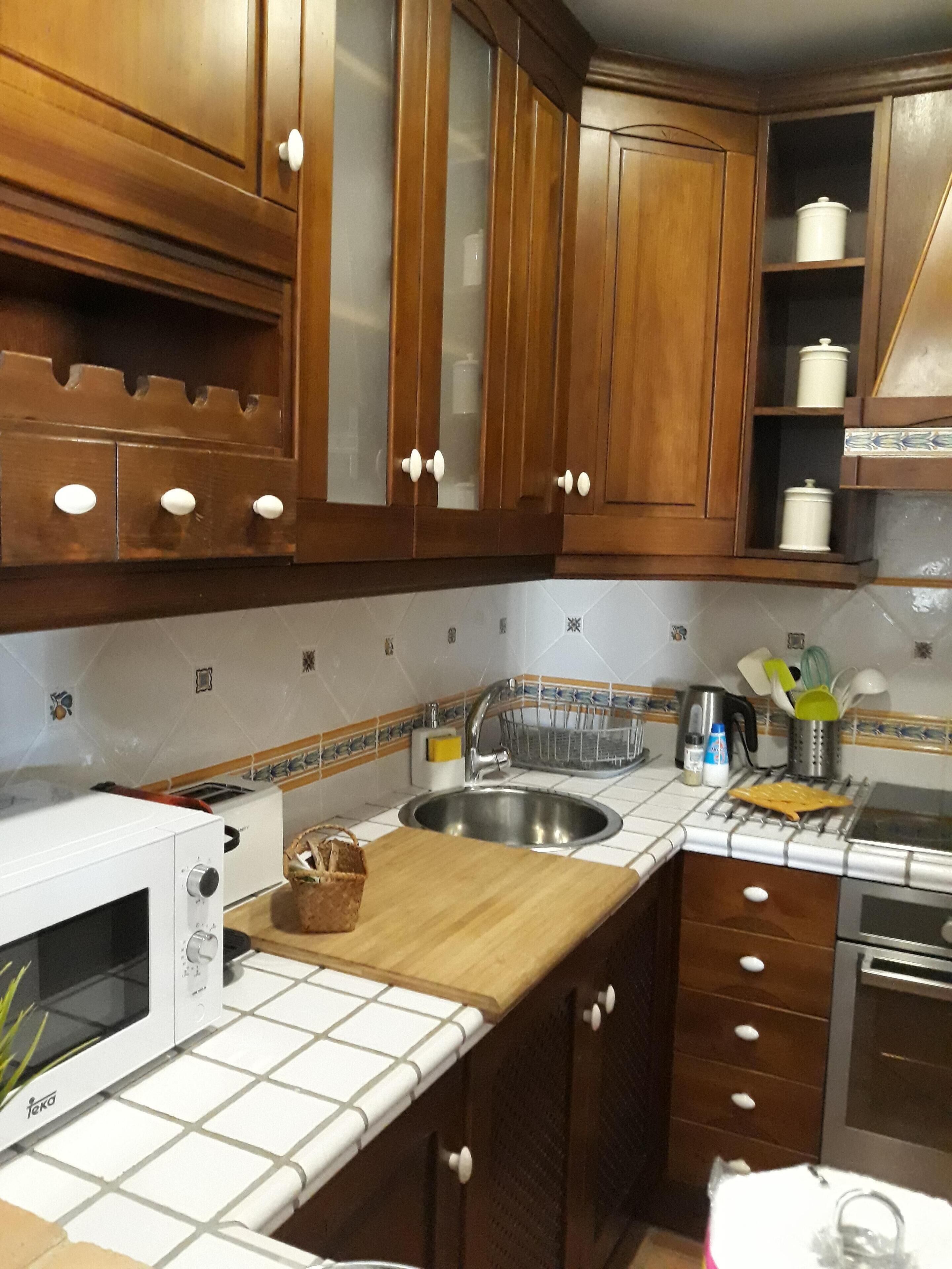 Une cuisine avec des meubles en bois, un évier en acier inoxydable, un four à micro-ondes et une cuisinière.